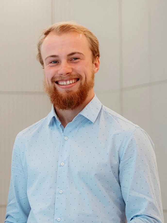 Malte Oevermann, blondes Haar und Bart, blaues Hemd, grauer Hintergrund