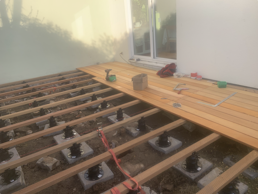 Verlegung der ersten Garapa-Terrassendielen auf der vorbereiteten Unterkonstruktion mit Stelzlagern während des Terrassenbaus in Frankfurt-Fechenheim
