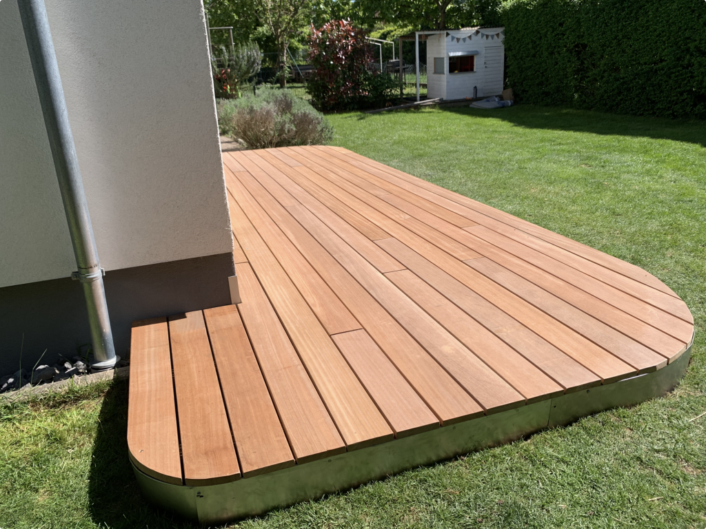 Maßgefertigte Bankirai-Terrasse mit gerundeter Vorderkante und hochwertiger Cortenstahl-Einfassung. Die Hartholzdielen wurden im wilden Verband verlegt und verdeckt befestigt.