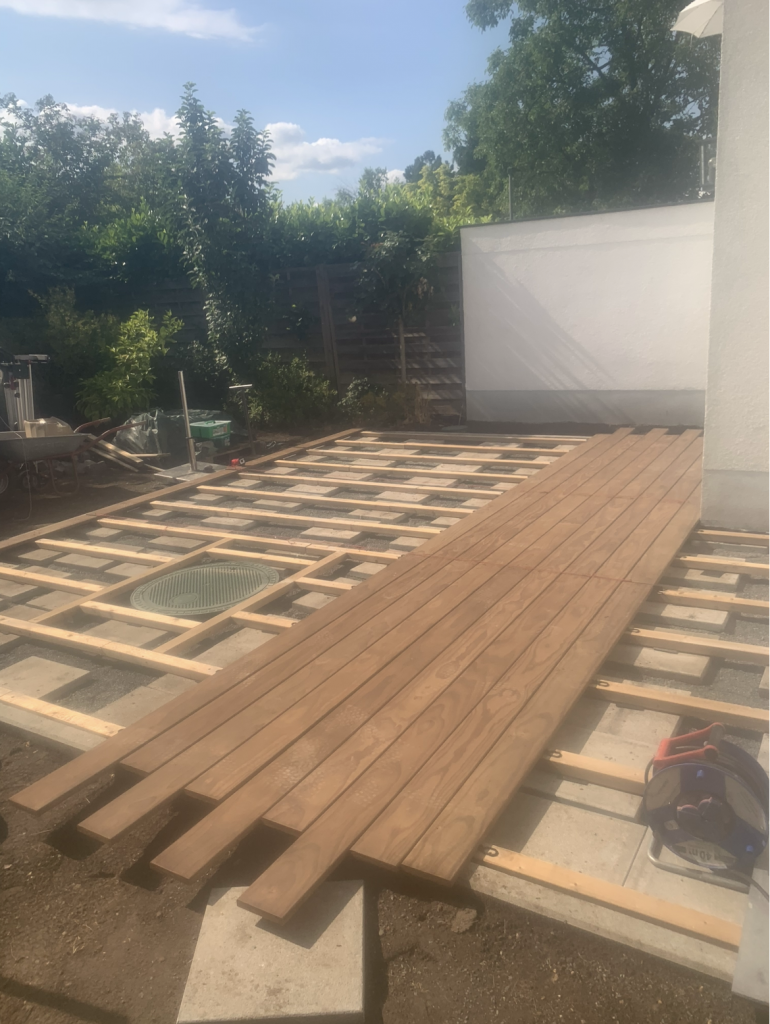 Beginn der Verlegung von Kebony-Terrassendielen auf einer Holzunterkonstruktion.